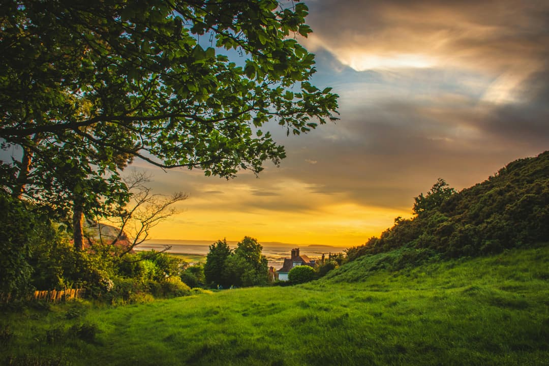 Prowall Free Wallpaper | A picturesque sunset over the lush, green countryside of Deganwy, Wales, capturing nature's beauty.
