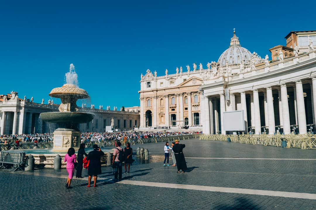 Prowall Free Wallpaper | St. Peter's Basilica and fountain in St. Peter's Square, Vatican City, showcasing iconic architecture and tourists.