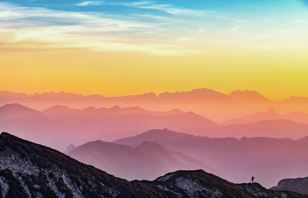 Prowall Free Wallpaper | Colorful sunrise over misty mountains in Altmünster, Austria with a lone hiker silhouette.