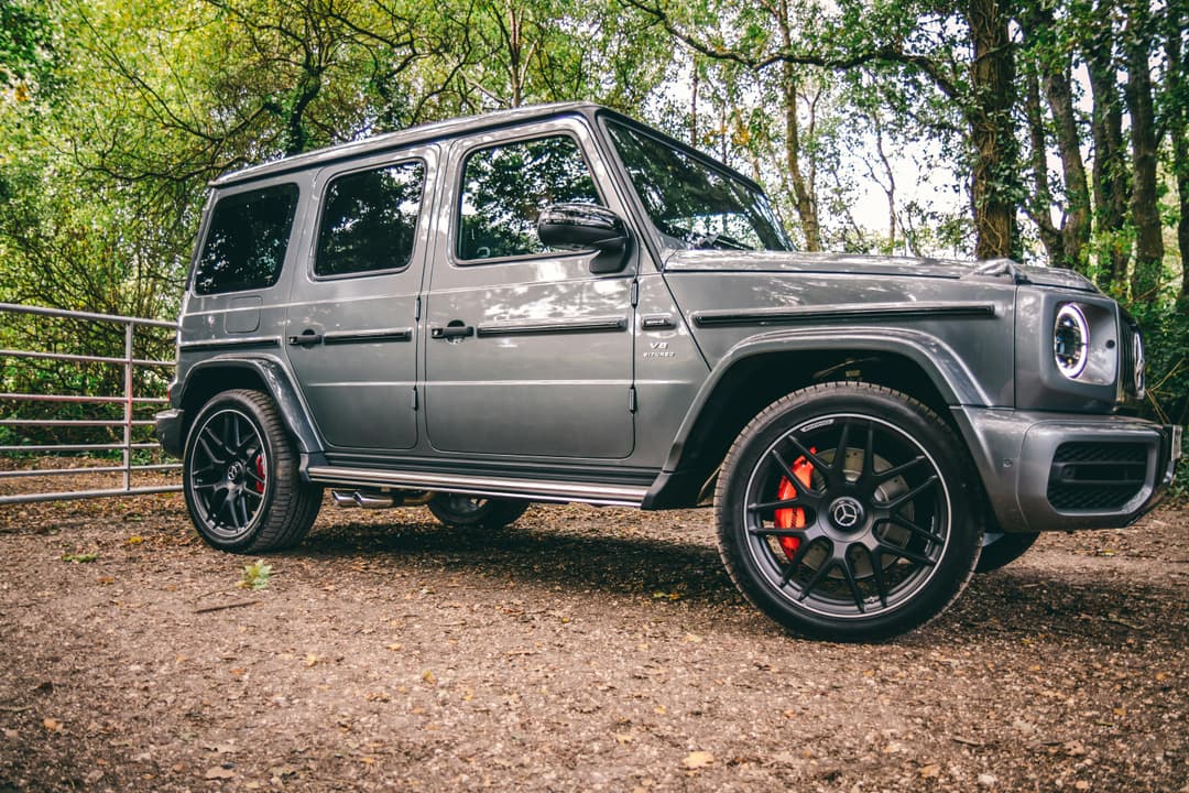 Prowall Free Wallpaper | A luxurious Mercedes-Benz SUV parked in a scenic wooded area, showcasing elegance and power.