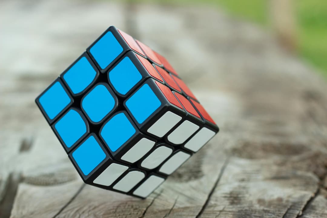 Prowall Free Wallpaper | Colorful Rubik's Cube resting on a wooden surface, showcasing vibrant geometric patterns.