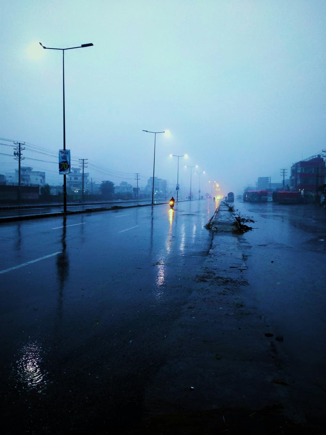 Prowall Free Wallpaper | Rain-soaked street at twilight with glowing streetlights and misty atmosphere.