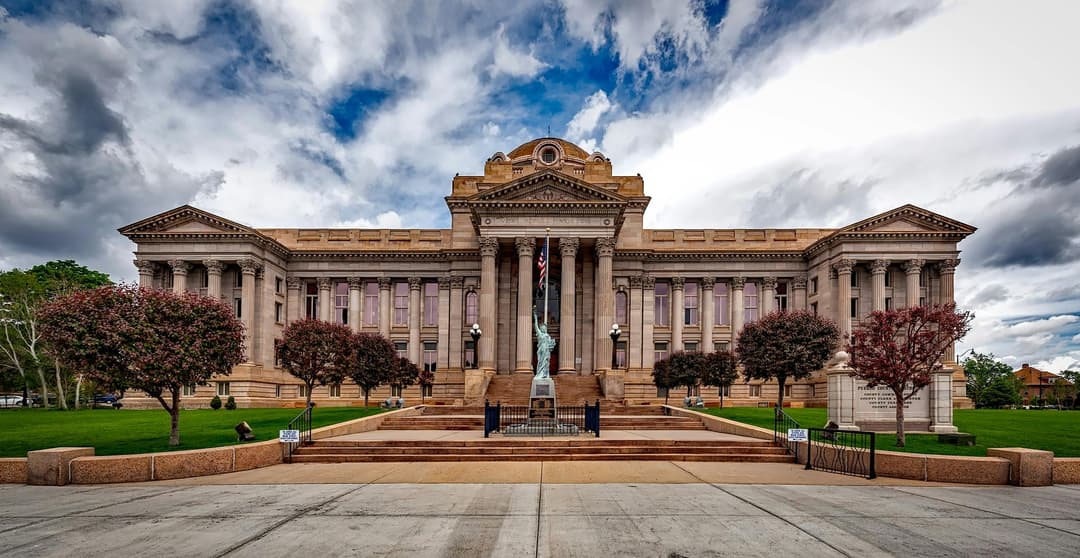 Prowall Free Wallpaper | Front view of a neoclassical courthouse building in Colorado with lush greenery.
