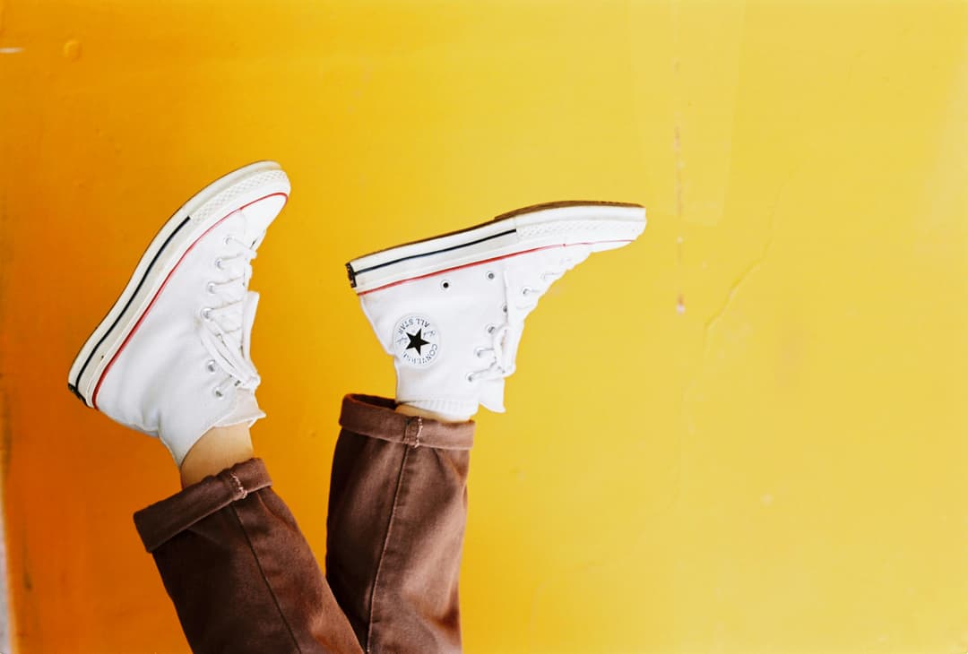 Prowall Free Wallpaper | Upside down image of white sneakers against a vibrant yellow background, showcasing trendy footwear style.