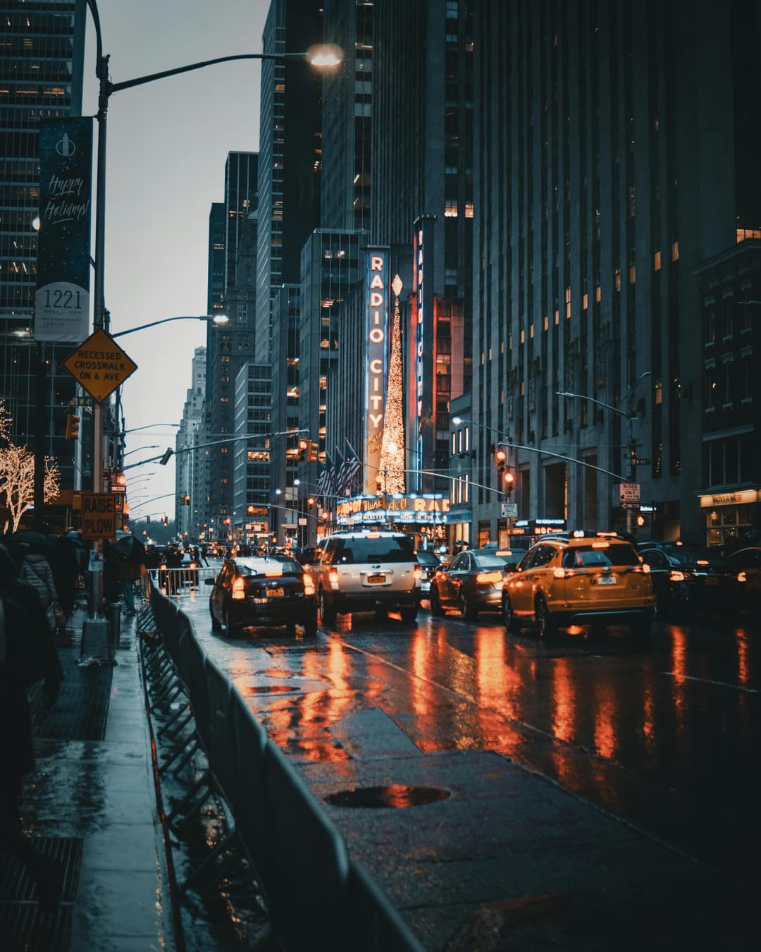 Prowall Free Wallpaper | Dramatic city street view of New York's Radio City at night with reflections and taxis.