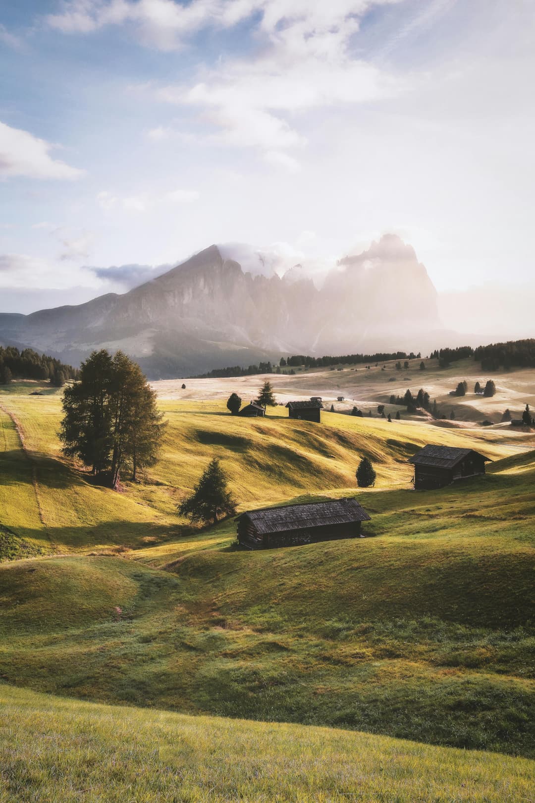 Prowall Free Wallpaper | Tranquil countryside view in Alpe di Siusi, Italy featuring lush greenery and distant mountains under a bright sky.