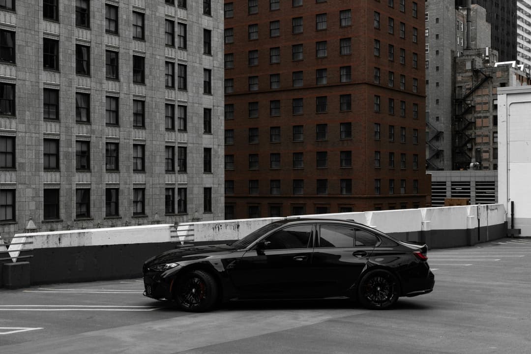 Prowall Free Wallpaper | A stylish black car parked on a rooftop amid Chicago's urban backdrop.
