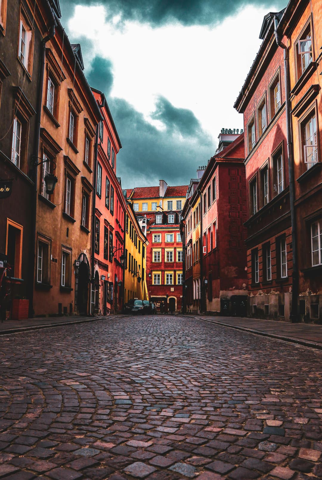 Prowall Free Wallpaper | Dramatic view of cobblestone street in Warsaw's Old Town, showcasing colorful historic architecture.