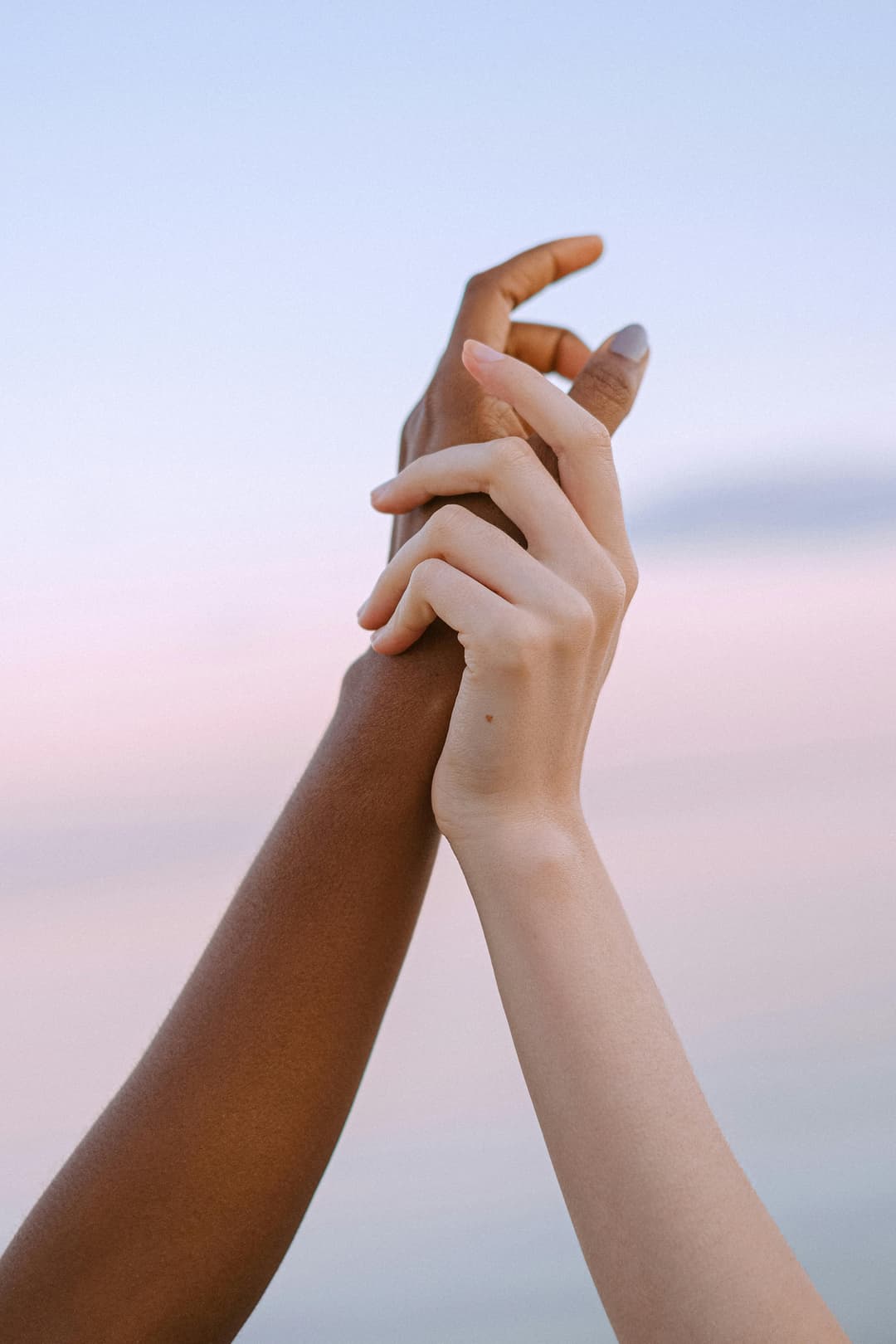 Prowall Free Wallpaper | Two diverse hands holding together, symbolizing unity and friendship at sunset.
