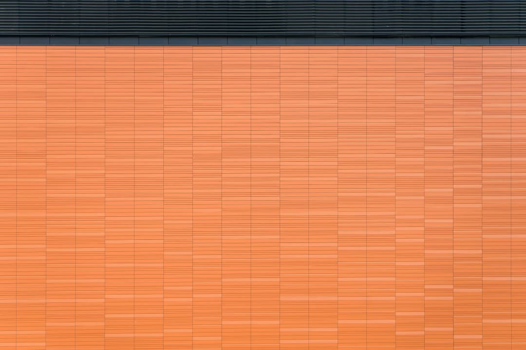 Prowall Free Wallpaper | Detailed view of an orange brick wall with horizontal lines and geometric pattern for architectural design background.