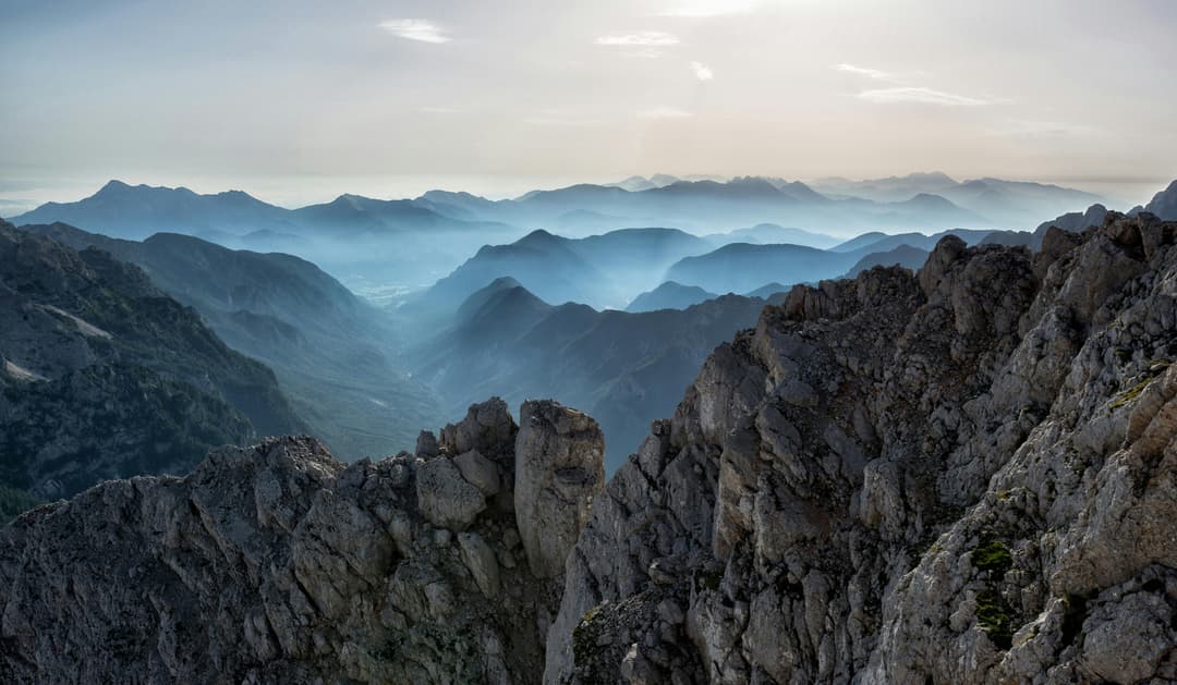 Prowall Free Wallpaper | Capture of a tranquil mountain range at dawn with misty valleys and rocky peaks.