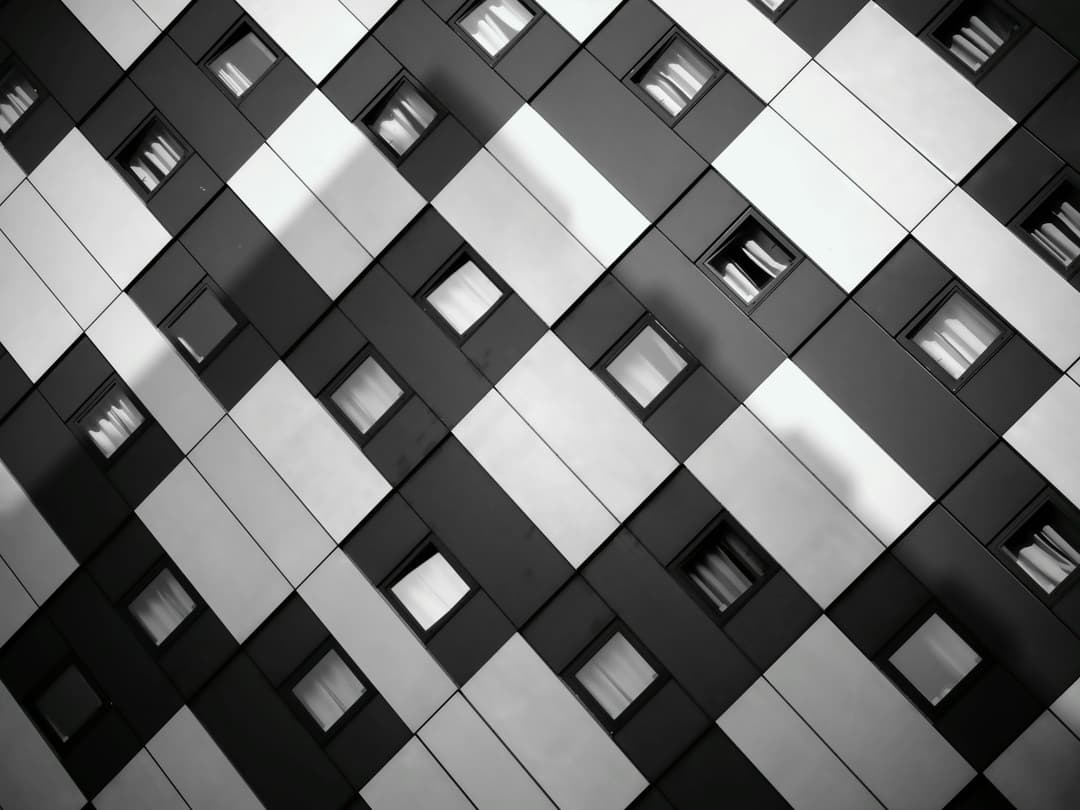 Prowall Free Wallpaper | A striking monochrome image of a modern building's geometric facade with windows.