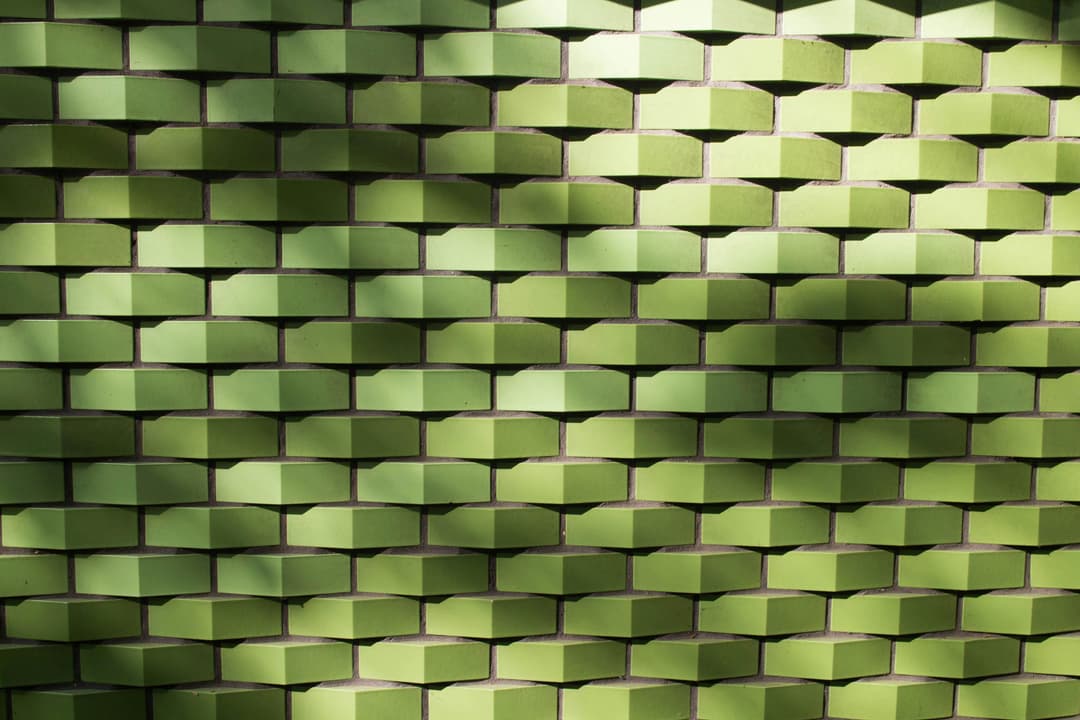 Prowall Free Wallpaper | Textured green tile wall with geometric pattern and light shadows, ideal for backgrounds.
