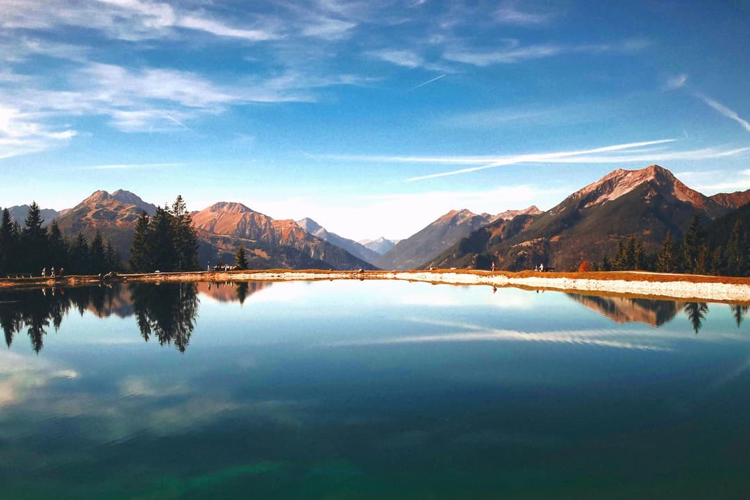 Prowall Free Wallpaper | Peaceful mountain lake reflecting the surrounding landscape under a stunning sunset sky.