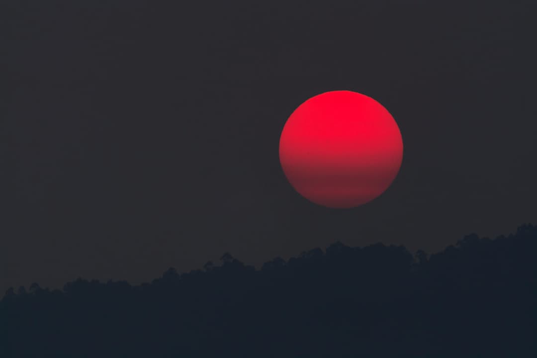Prowall Free Wallpaper | A captivating blood moon rising over a silhouette of hills, capturing the beauty of twilight.