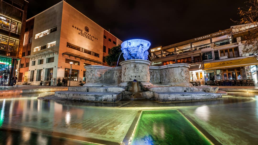 Prowall Free Wallpaper | Night view of the illuminated Morosini Fountain in Iraklio, Greece, showcasing the vibrant urban architecture.