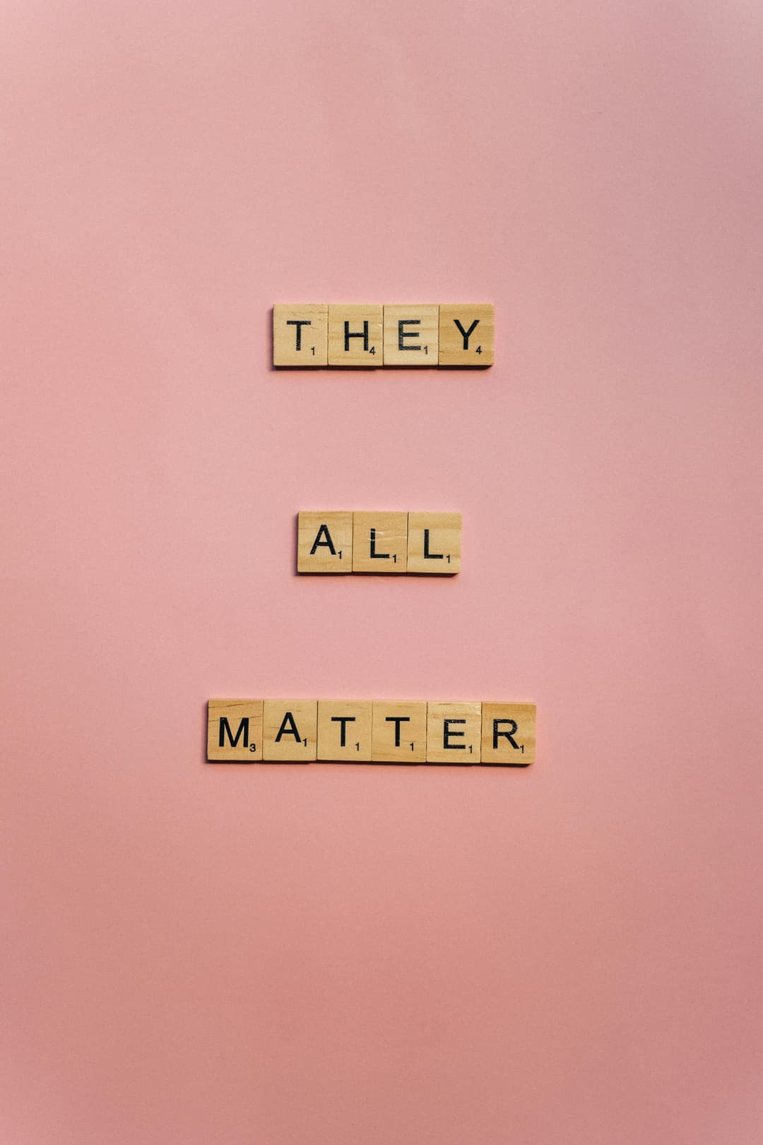Prowall Free Wallpaper | Scrabble tiles spelling 'They All Matter' on a soft pink background.